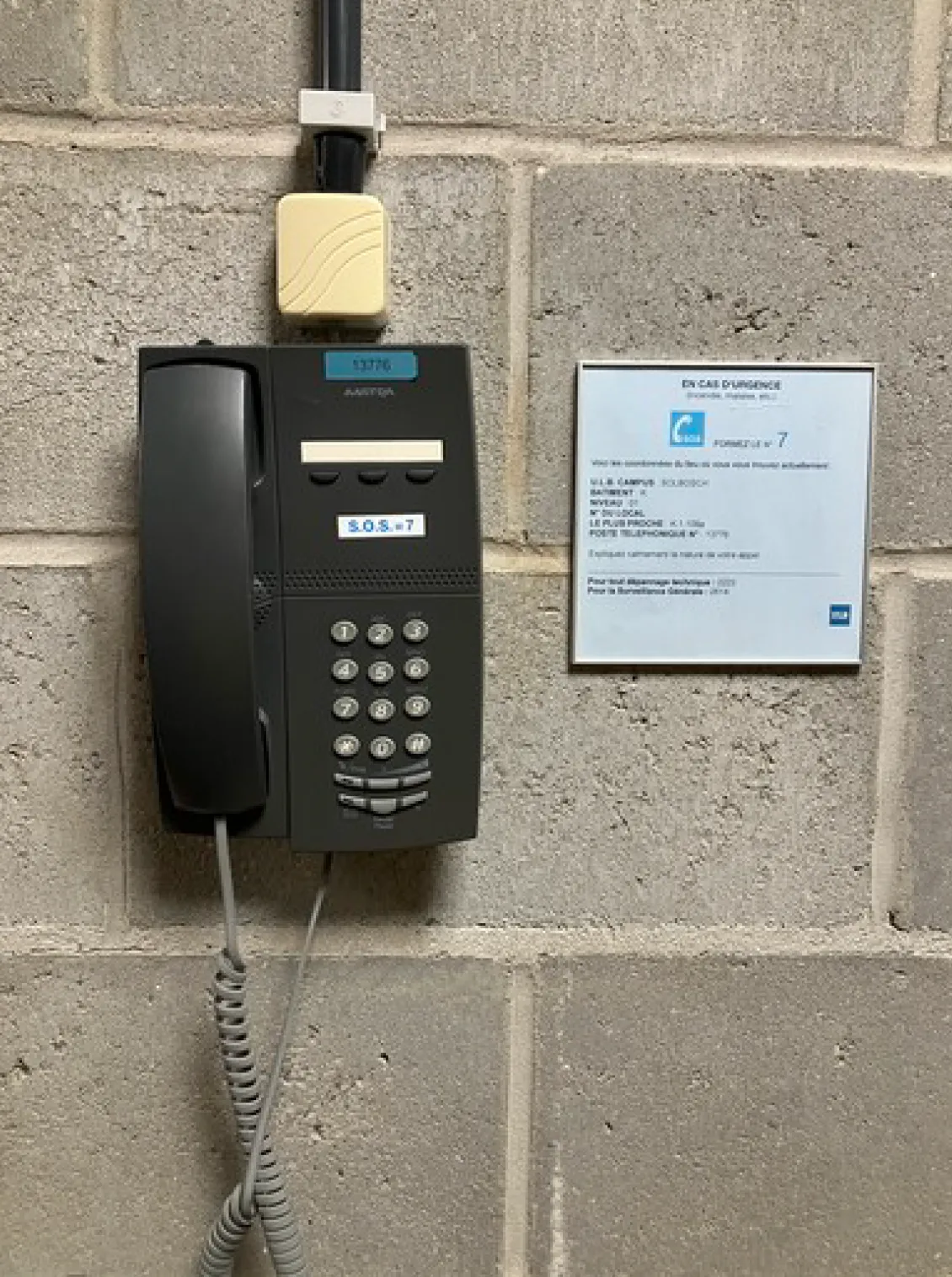 Black phone attached to a wall with information text next to it