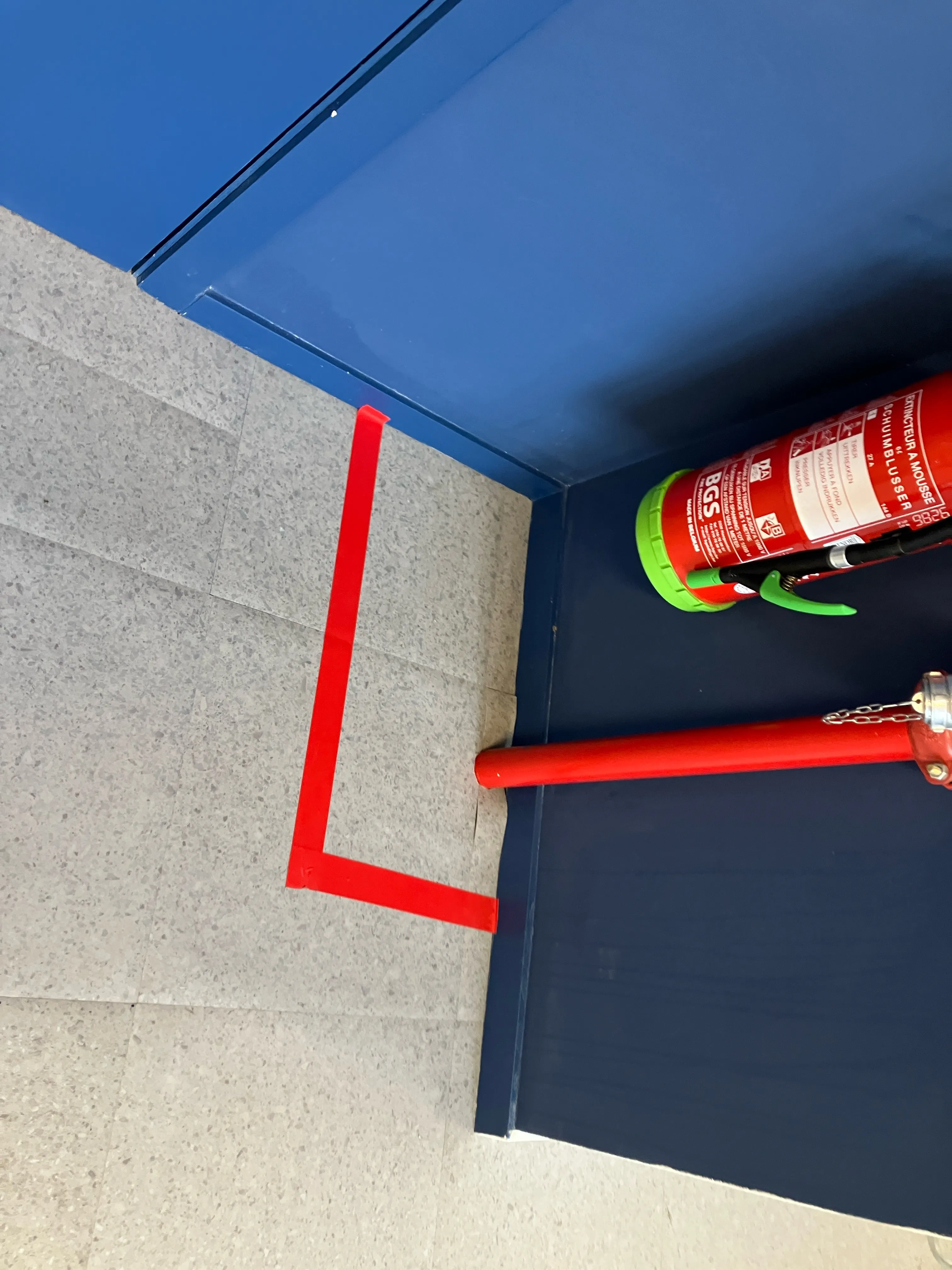Fire extinguisher surrounded with red tap on the floor